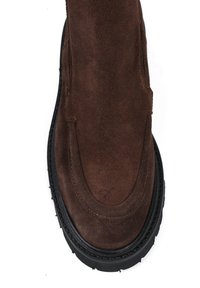 Brązowe zamszowe botki za kostkę z okrągłym noskiem, gumową podeszwą i minimalnym detale szycia. Gładka tekstura z matowym wykończeniem.