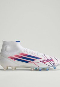 Λευκό παπούτσι ποδοσφαίρου με μπλε και κόκκινες λεπτομέρειες, σχεδιασμό υψηλής κάλτσας στον αστράγαλο και διαφανείς ή καρφιά σε ανοιχτό γκρι φόντο.