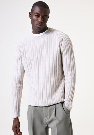 Suéter de punto acanalado gris claro con cuello redondo y mangas largas, combinado con pantalones sueltos de corte ligero en gris claro.
