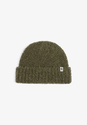 Olive green knitted beanie hat with folded ribbed cuff and small white fabric tag on cuff's edge.