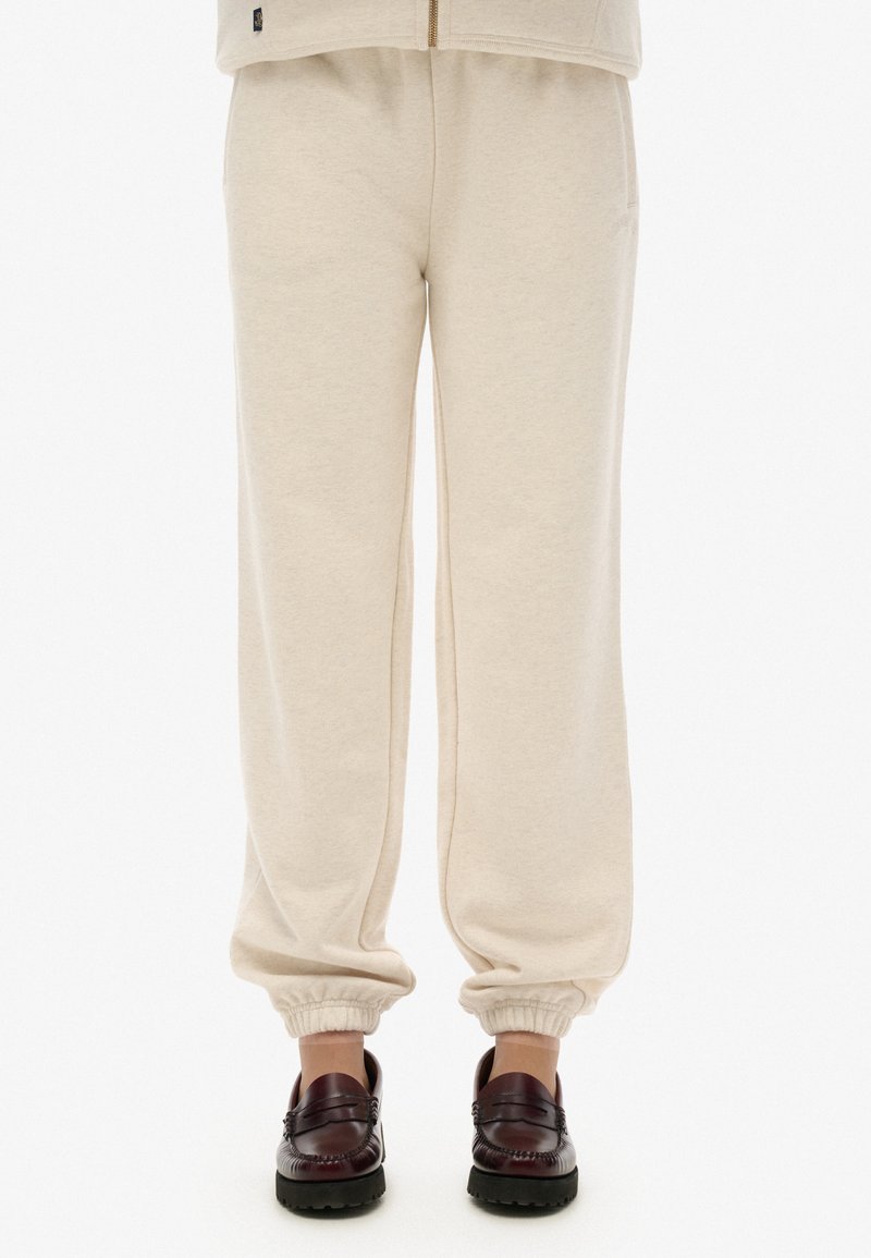 Pantaloni della tuta beige con cintura elastica e polsini, realizzati in morbido cotone, con vestibilità rilassata e tasche laterali.