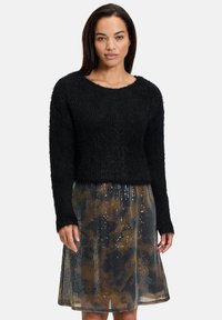 Schwarzer, kuscheliger Pullover mit langen Ärmeln, kombiniert mit einem glänzenden Rock aus braunen und schwarzen Pailletten, der eine lockere Passform und einen elastischen Bund hat.