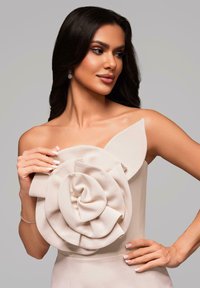 Bežové šaty bez ramínek s velkým texturovaným detailem růže na těle a strukturovaným akcentem listu, s hladkým povrchovým zpracováním látky.