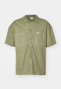 Camicia a maniche corte con bottoni in cotone verde oliva. Presenta due tasche frontali, un colletto e un orlo dritto. Etichetta del marchio visibile sulla tasca sinistra.