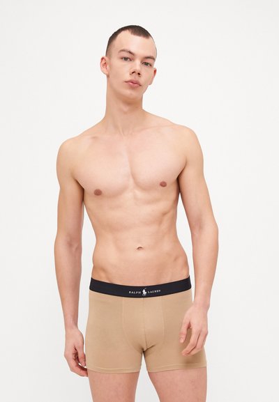 Bež bombažne bokserice z črnimi elastičnimi pasom, ki nosi logo Ralph Lauren, gladka tekstura in prilegajoča zasnova.