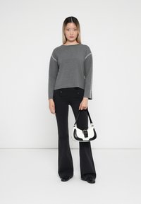 Gray sweater with striped accent along sleeves, paired with high-waisted black flared pants and a black-and-white handbag.