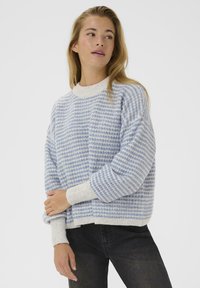 Blue and white striped knit sweater with a ribbed neckline and cuffs, featuring a loose fit and soft texture. Worn with black pants.