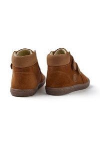 Zapatillas altas de ante marrón con un interior suave, que presentan correas de velcro y una punta redondeada. Parte superior texturizada y suela de goma.