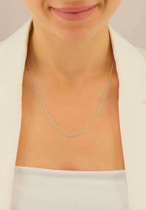 Collana in argento esposta su un collo, caratterizzata da un design delicato e sottile con una superficie liscia e lucida. Aspetto minimalista.