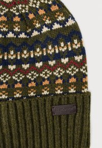 Kootud beanie oliivrohelises värvitoonis, millel on geomeetriline muster mereväe sinises, valges ja oranžis. Omab soonikule õmmeldud äärist ja brändi nahkmärgistust.