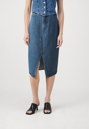 Denimskjørt med en tettsittende silhuett, kne-lengde, med en frontslits og dekorert med små nagler. Brukt med svarte åpen-tå hæler.