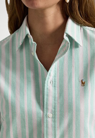 Gaiši zaļa svītraina krekls ar baltām un rozā vertikālām svītrām, pogu aizdare un maza izšūta logotips uz krūtīm.