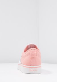 Sneaker Adidas Nizza rosa vista da dietro, con suola bianca e etichetta del marchio su uno sfondo bianco semplice.