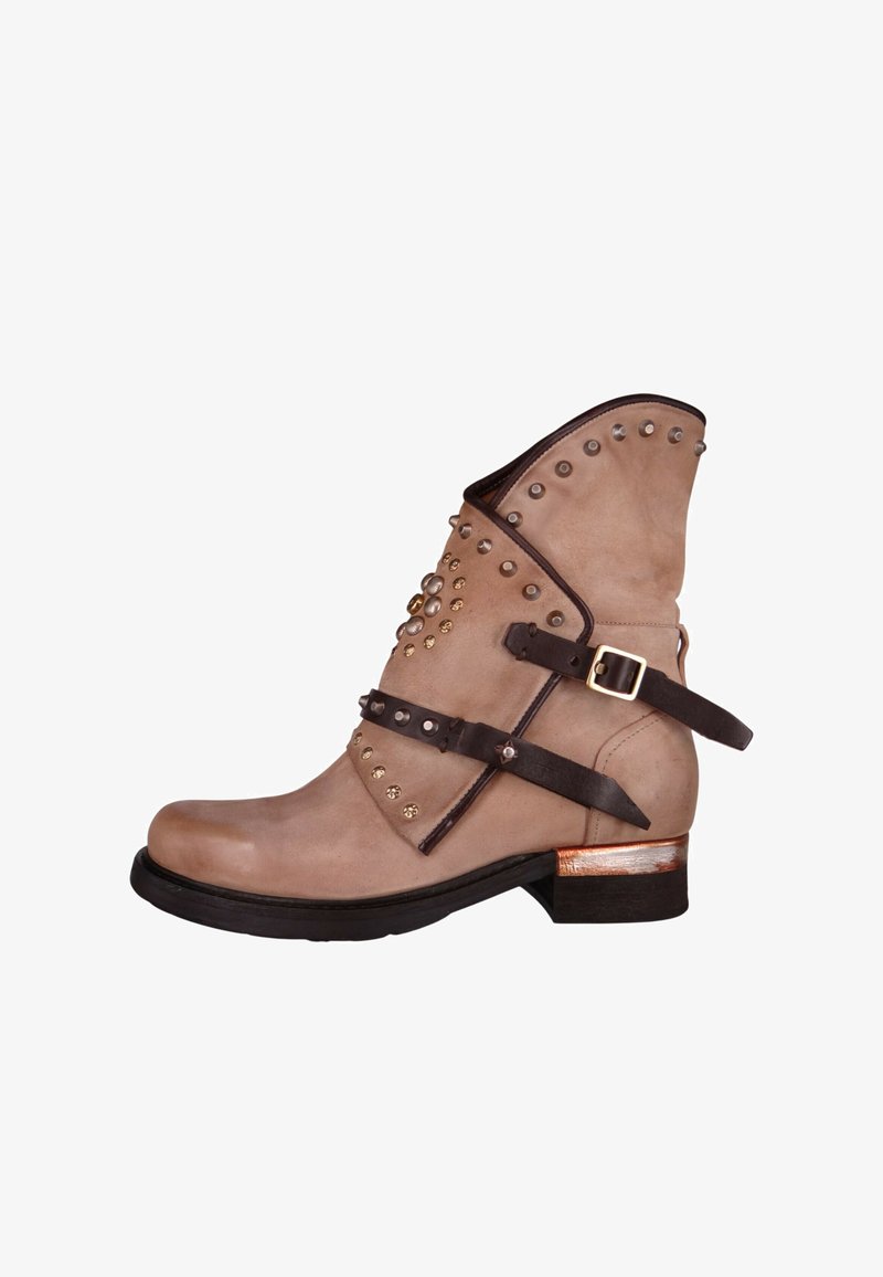 Beżowy zamszowy botek za kostkę z szpiczastym noskiem, ozdobiony brązowymi skórzanymi paskami, metalowymi ćwiekami oraz niskim drewnianym obcasem z złotym akcentem.