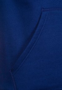 Sweat-shirt bleu marine avec une poche kangourou à l'avant, une texture douce et des coutures côtelées sur les bords.