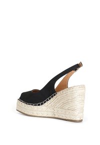 Svarta canvas slingback kilar med en sula av jute-rep, med öppen tå och ett strukturerat vävt mönster längs klacken.