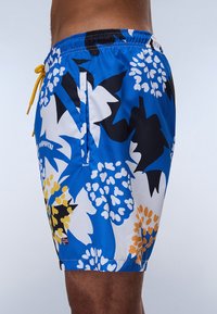 Svømmebukser med et livligt blomsterprint i blå, sort, gul og hvid. Fremstillet af letvægtsstof med elastisk talje og snøre.