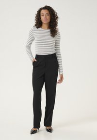 Grå och vit randig ribbad långärmad topp i kombination med högt midje svarta byxor och svarta spetiga klackar. Minimalistisk och skräddarsydd design.