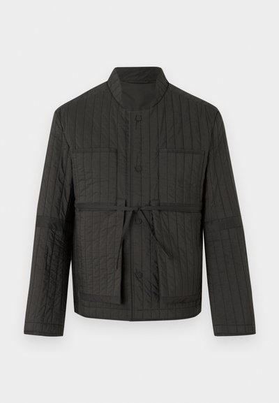 Veste matelassée noire avec col montant, boutons-pression à l'avant, deux poches poitrine et ceinture à nouer à la taille.