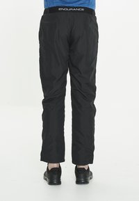 Svarta vadderade byxor med en slät yta, med en bred elastisk midja märkt "ENDURANCE" och en rak bendesign.