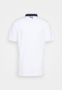 Polo blanc avec un col bleu marine, des manches courtes et un logo au dos. Le tissu semble lisse avec une coupe classique.