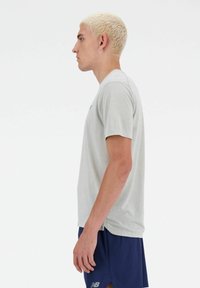 Lichtgrijs sportshirt met korte mouwen en een gestructureerd oppervlak, ronde hals en subtiele branding op de borst, gecombineerd met marineblauwe shorts.