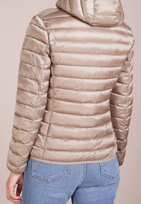 Helle beige Pufferjacke, gestepptes Design, mit Kapuze, glänzende Oberfläche, schmaler Schnitt, elastische Bündchen und unterer Saum mit kontrastierendem Besatz.