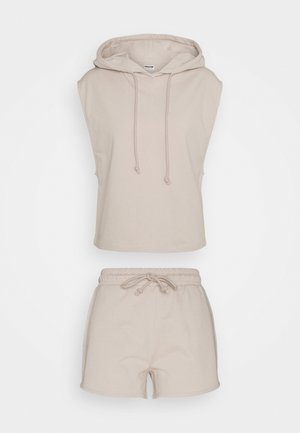Beżowa bezrękawna bluza z kapturem ze sznurkami w połączeniu z pasującymi szortami z elastycznym pasem i sznurkiem, prezentowane na jednolitym tle.