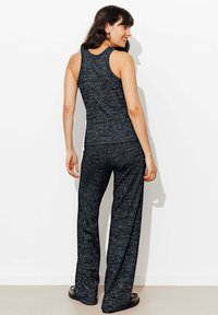 Ensemble de débardeur tricoté noir et gris avec un pantalon large, présentant une coupe ajustée et un motif texturé, vu de dos. Tissu lisse.