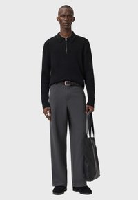 Black knit zip-up sweater, grey wide-leg trousers, black leather bag, black shoes. Smooth texture with a subtle pattern and fitted design.