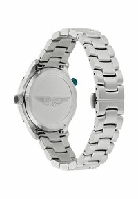 Orologio da polso in metallo argentato con bracciale a maglie, mostra il retro della cassa inciso con il logo Aston Martin e due corona laterali.