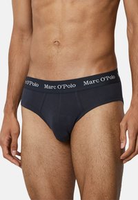 Męskie czarne bawełniane slipy z szerokim elastycznym paskiem, na którym znajduje się białe logo "Marc O’Polo", zaprojektowane dla dopasowanego kroju.