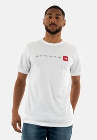 Camiseta blanca de manga corta hecha de algodón. Presenta un logo rojo y el texto "NUNCA DEJES DE EXPLORAR" impreso en el pecho.