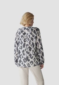Langärmlige Bluse aus leichtem, glattem Stoff mit einem Schwarz-Weiß-Leopardenmuster. Verfügt über Raffung an den Schultern.