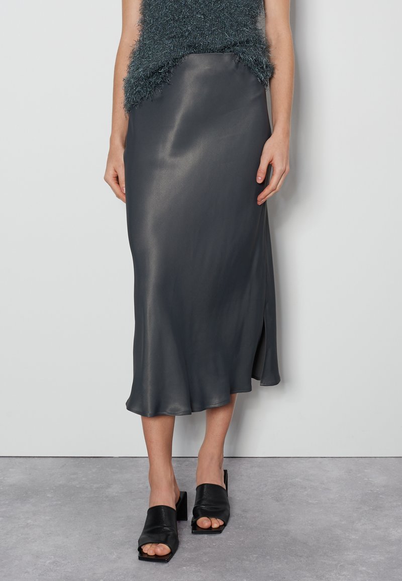 Dunkelgrauer Satin-Midikleid mit Seitenschlitz, leicht und mit glatter Textur, kombiniert mit schwarzen Mules mit Blockabsatz.