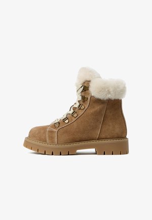 Bruine suède enkelbootjes met een fluffy romige bontkraag, vetersluiting aan de voorkant, metalen oogjes en een dikke, robuuste rubberen zool.