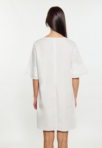 Weißes Kleid mit kurzen, ausgestellten Ärmeln, rundem Ausschnitt und Reißverschluss hinten. Glattes, leichtes Material mit einem schlichten Design.