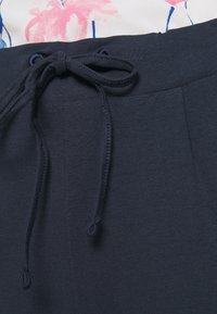 Marinblå sweatpants med elastisk midja, snörningsdetaljer och sidofickor, tillverkade av mjukt, strukturerat tyg.