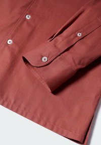 Roestkleurig shirt met lange mouwen en een knoopsluiting aan de kraag; heeft witte knopen en manchetten; gemaakt van glad, gestructureerd stof.