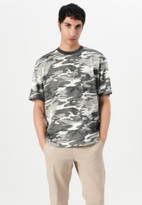 Camo t-skjorte i grå og hvite nyanser, med rund halsutringning, korte ermer og en logo detalj på brystet. Casual passform.
