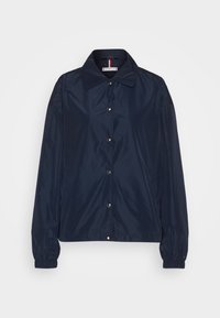 Granatowa lekka kurtka, z kołnierzem, zatrzaskami, elastycznymi mankietami i gładką, błyszczącą fakturą. Prosty design, bez wzorów.