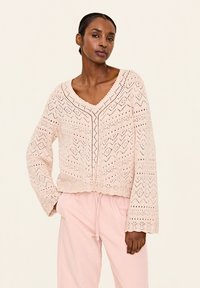 Helles rosa gestricktes Sweatshirt mit V-Ausschnitt, langen Ärmeln und komplizierten Rautenmuster- und Zickzackmustern. Verkürzter Stil mit gewelltem Saum.