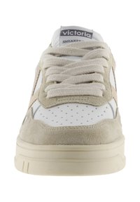 Sneaker bianco e beige con tomaia in suede testurizzato, punta perforata, lacci rotondi e suola in gomma. Logo visibile sulla linguetta.