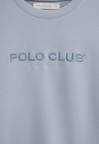 Felpa azzurro chiaro con "POLO CLUB" ricamato in blu scuro e "ESTABLISHED 2012" in lettere più piccole sotto il logo.
