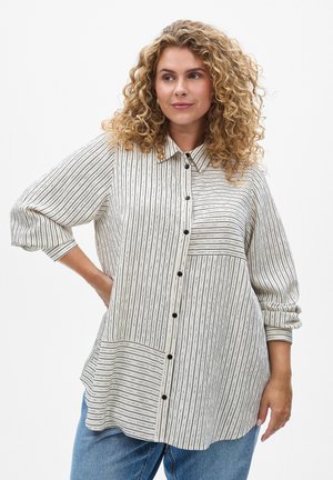Losse, lange mouw shirt in gebroken wit met zwarte verticale strepen. Beschikt over een knoopsluiting aan de voorkant en een zijzak. Zachte stoftextuur.