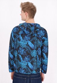 Hooded jacket van lichte stof met een blauw tropisch bladerenpatroon op een zwarte achtergrond. Inclusief een trekkoordcapuchon en lange mouwen.