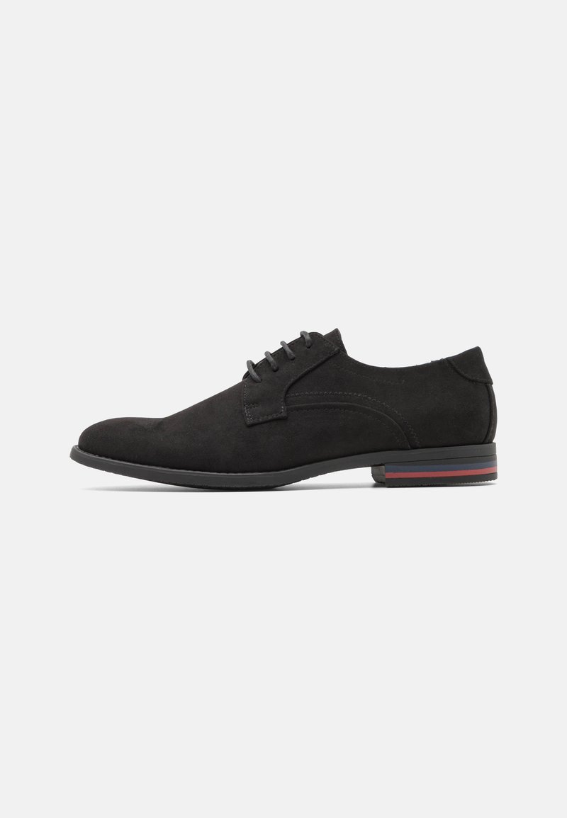 Chaussures habillées en daim noir avec un design épuré, un profil slim, un système de laçage et une subtile rayure sur la semelle.
