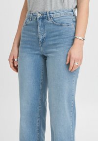 Hellblaue Jeans aus Denim mit hoher Taille, geradem Schnitt und Fünf-Taschen-Design. Verfügt über einen Frontknopfverschluss und einen ausgewaschenen Look.