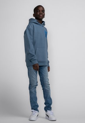 Felpa con cappuccio in tessuto blu ardesia, con tasca frontale a marsupio e dettaglio grafico blu sul petto. Abbinata a jeans azzurri.