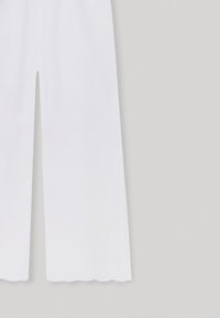 Bílé lněné kalhoty s širokými nohavicemi, s volánkovým lemem a detaily z očkového materiálu podél látky. Lehký a prodyšný materiál.